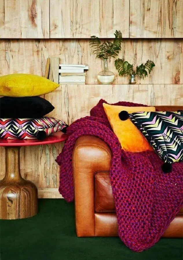 Sala decorada com parede rústica de madeira e sofá cor caramelo de couro Foto Pinterest