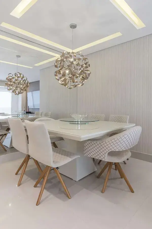 Sala moderna com mesa de jantar branca e cadeiras da mesma cor com iluminação de lustre redondo