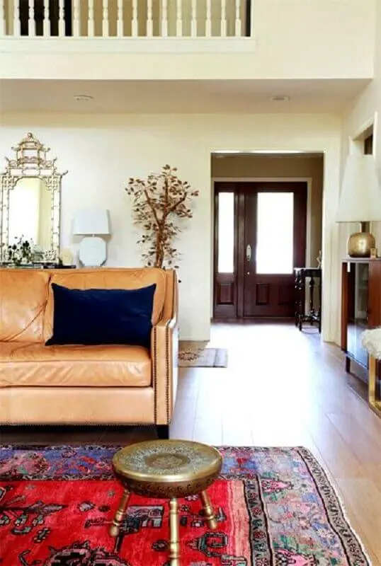 Sala simples decorada com sofá cor caramelo e tapete vermelho Foto Jeito de Casa