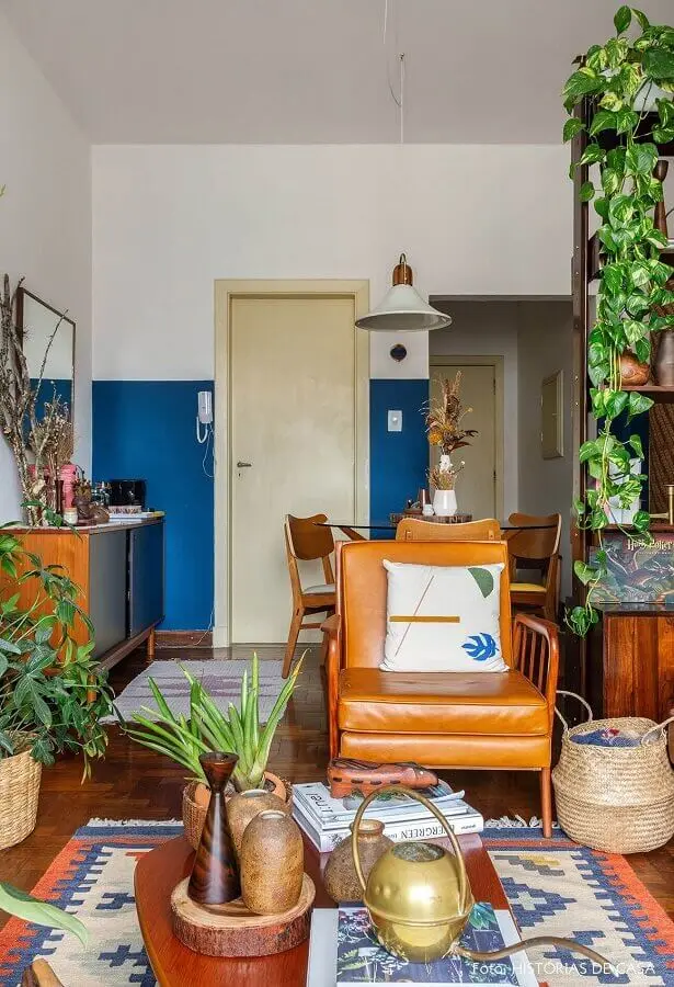 Sala simples decorada com vasos de plantas e poltrona cor caramelo de couro Foto Histórias de Casa