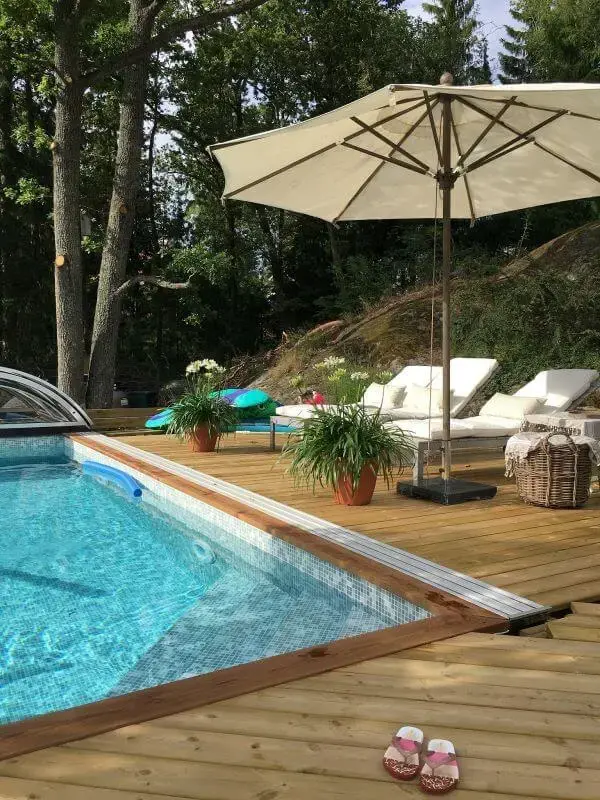 Área de piscina moderna com guarda sol para proteger a família dos raios uv
