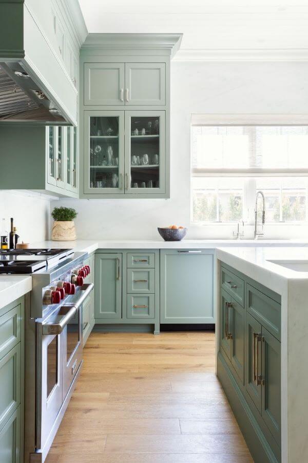 Cozinha com armários verde sage e bancada de mármore branco 
