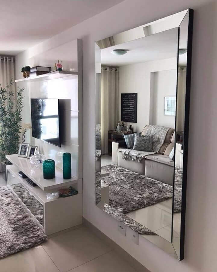 Espelho grande na sala de estar branca decorada com tapete felpudo e painel para TV Foto Art + Moveis Espelhados