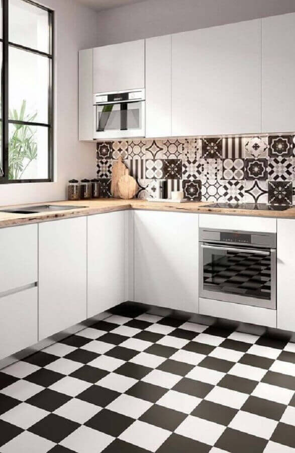 Gabinete branco para cozinha de canto decorada com bancada de madeira e piso xadrez Foto Decor Facil