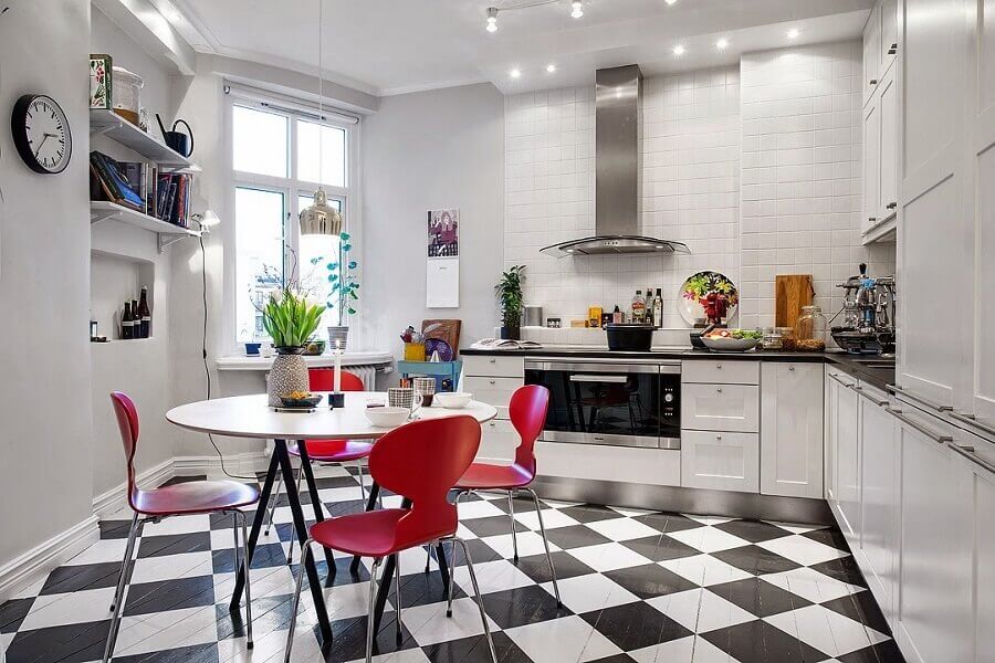 Gabinete branco para cozinha de canto decorada com cadeiras vermelhas e piso xadrez Foto Jurnal de Design Interior