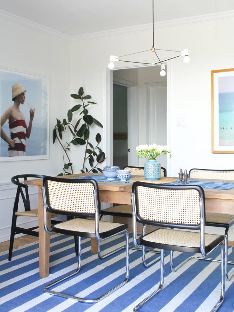 Mesa de jantar de madeira com cadeira cesca e tapete azul e branco
