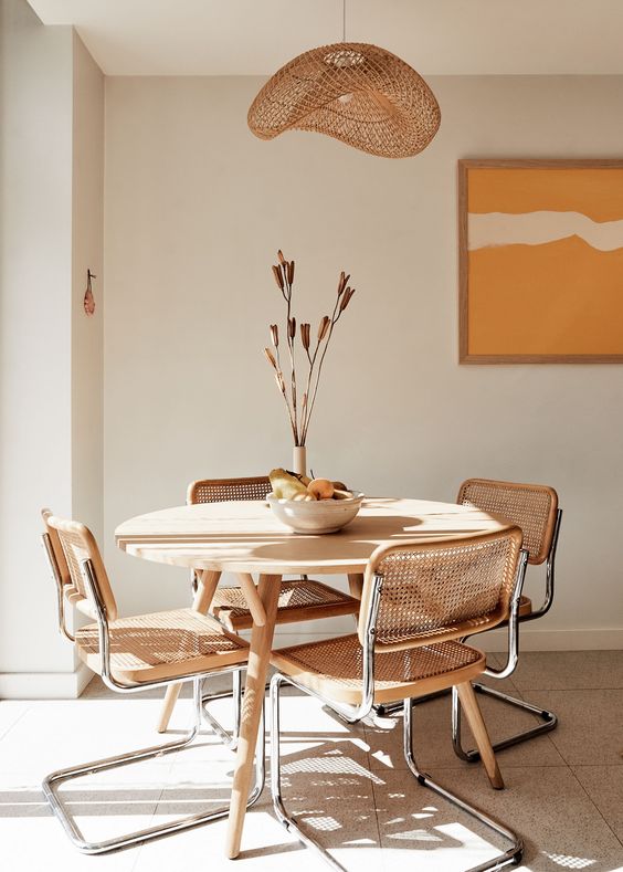 Mesa de jantar de madeira com cadeira cesca sem braço e decoração boho