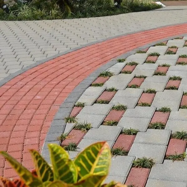 O piso intertravado vermelho forma lindas composições no chão da área externa com jardim. Fonte: Betonart Concretos