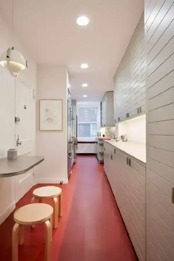 Piso vermelho e armários brancos decoram a cozinha. Fonte: Architectural Digest