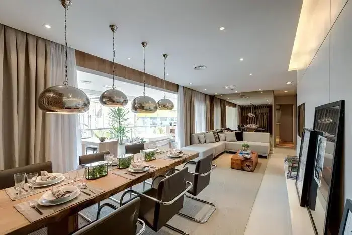 Sala de jantar de apartamento de luxo pendentes metálicos e mesa de madeira ampla. Fonte: Carlos Rossi