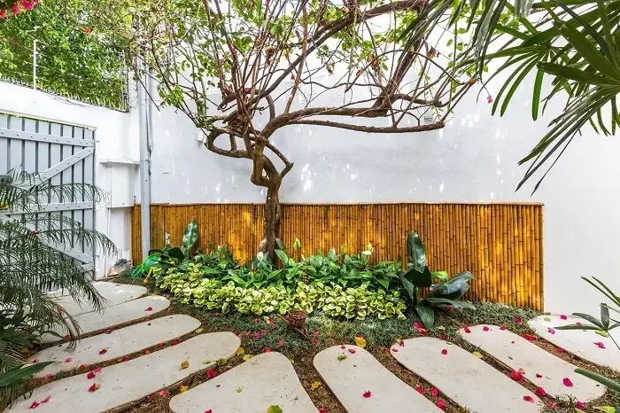 Área externa decorada simples com parede de bambu e pisantes de concreto. Fonte: BY Arq&amp;Design