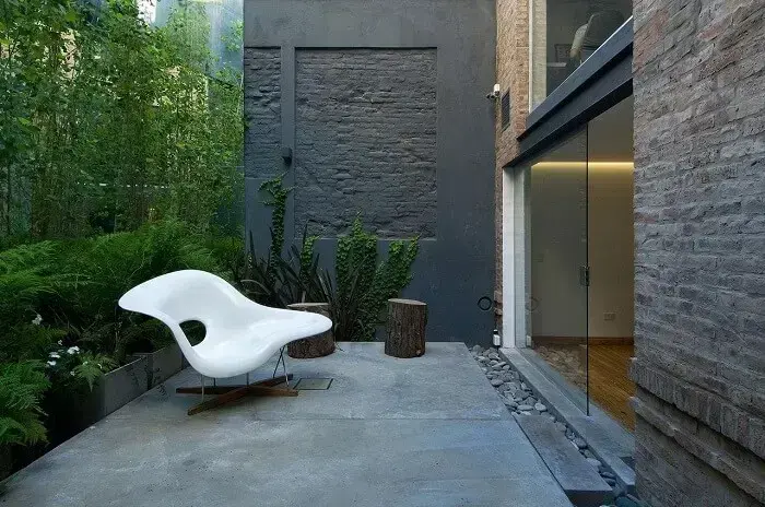 Área externa simples com cadeira acrílica branca criativa e vegetação natural. Fonte: Estudio Sespede Arquitectos