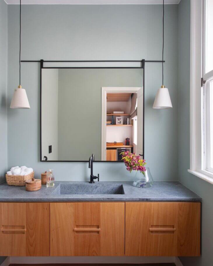 Banheiro com bancada de mármore cinza e armário de madeira