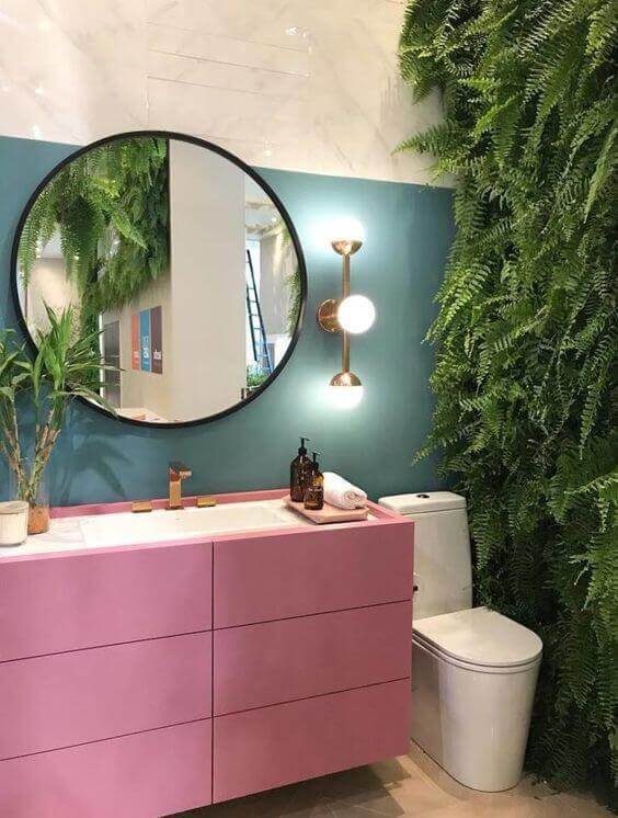 Banheiro retro e colorido com moldura redonda preta no espelho e parede de plantas