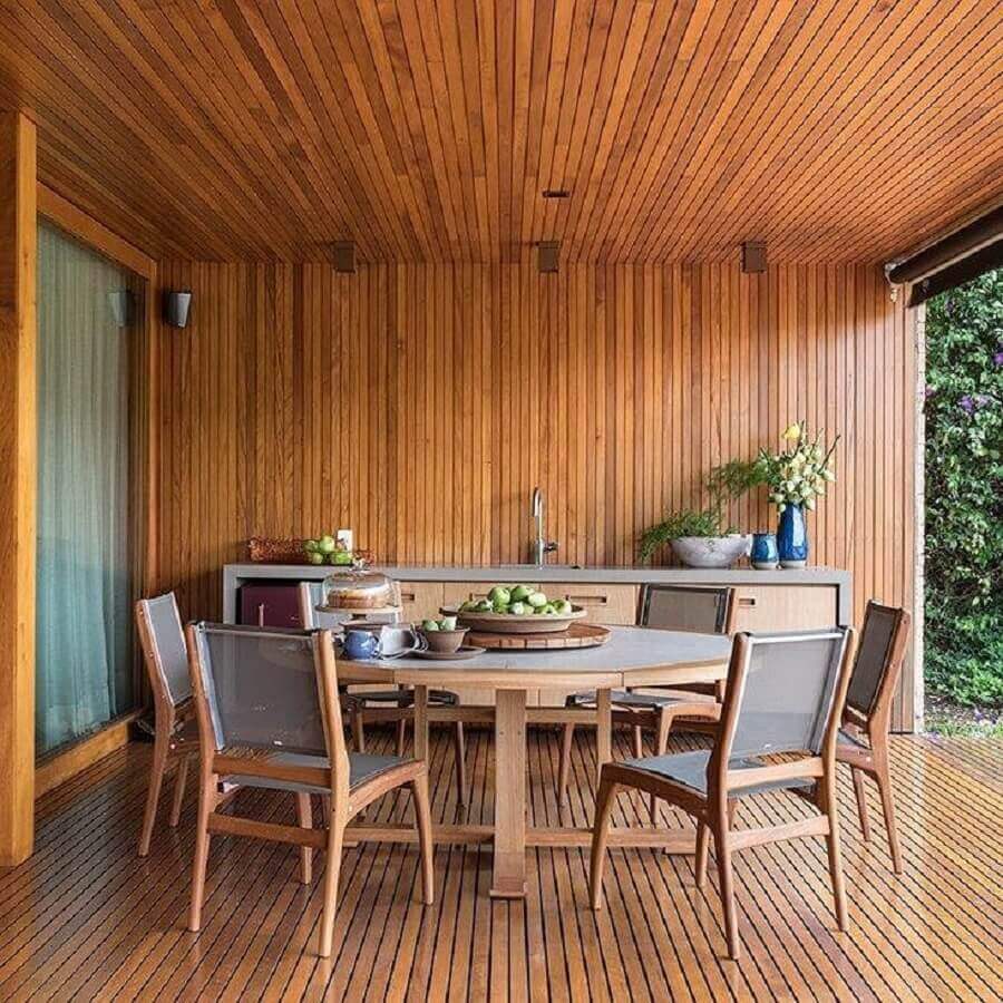 Casa com varanda decorada com mesa redonda e lambri de madeira Foto Tres Arquitetura