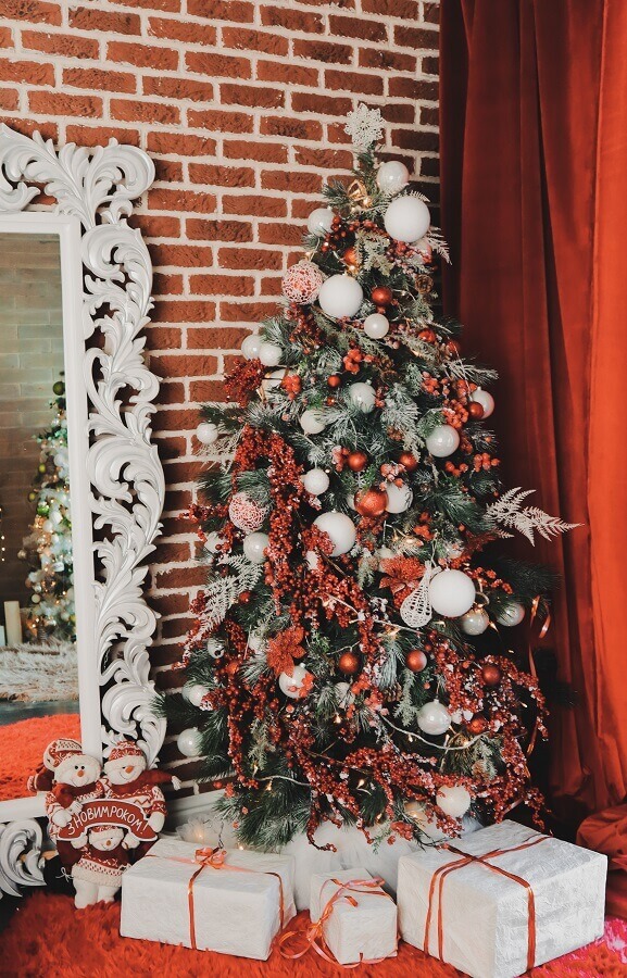 Como montar árvore de Natal vermelha e prata para decorar sala com parede de tijolinho Foto Unsplash