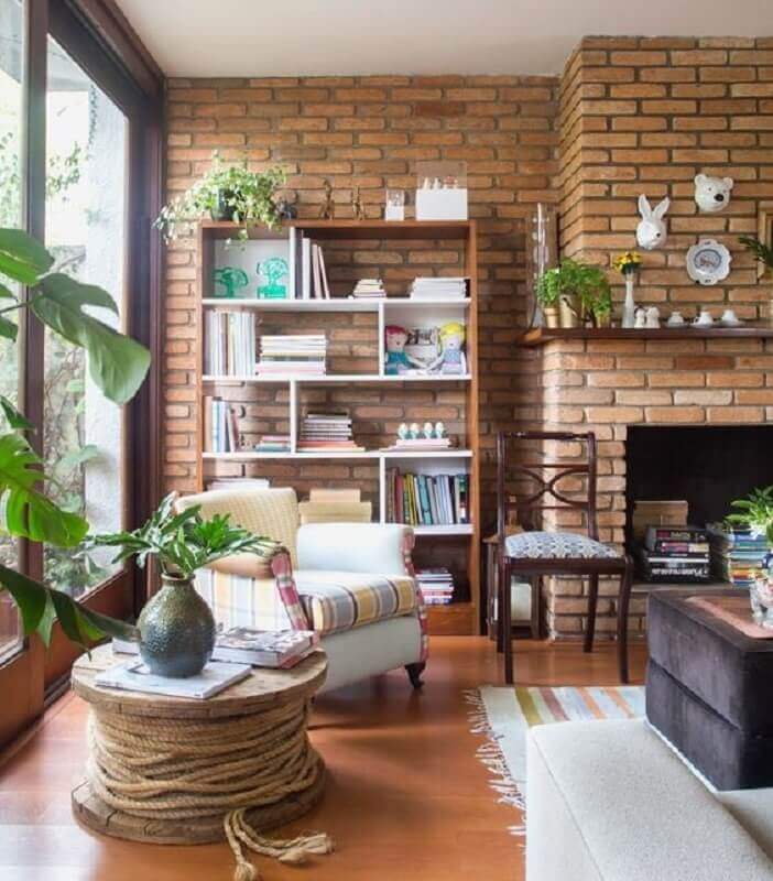 Estante de livros para decoração de sala rústica com lareira e parede de tijolinho Foto Rafaela Paoli