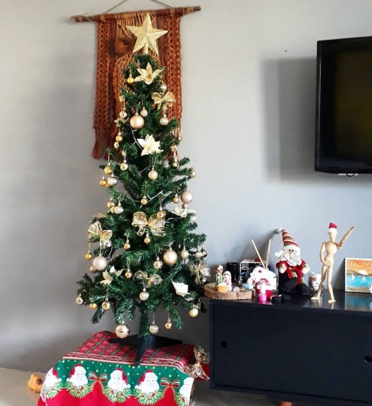 Laços para árvore de natal dourada e pequena perto do painel
