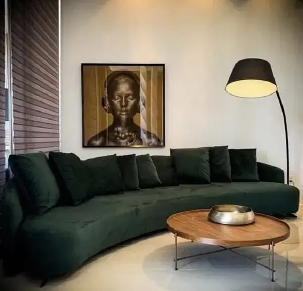 Mesa de centro de madeira e sofá curvo verde decoram a sala. Fonte: Ovoo Recife