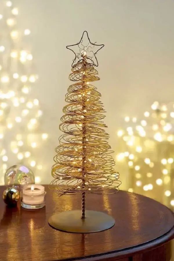 Mini árvore de natal dourada decora a mesa lateral da sala. Fonte: Decor Fácil