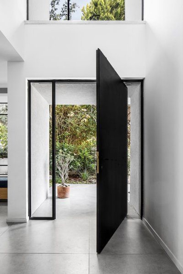 Porta pivotante preta na entrada de casa moderna 