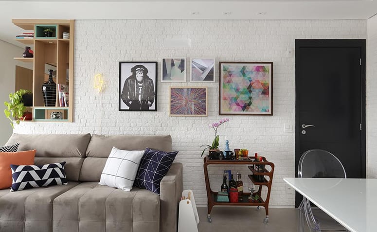 Porta preta na sala de estar decorada com quadros modernos e sofá neutro