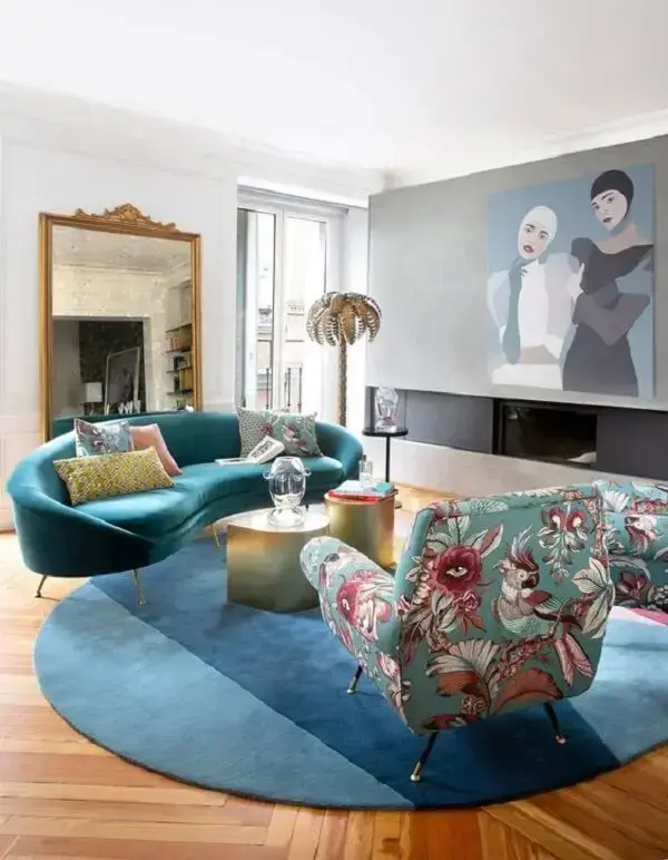 Sala com sofá curvo azul e poltronas estampadas. Fonte: ELLE Decor