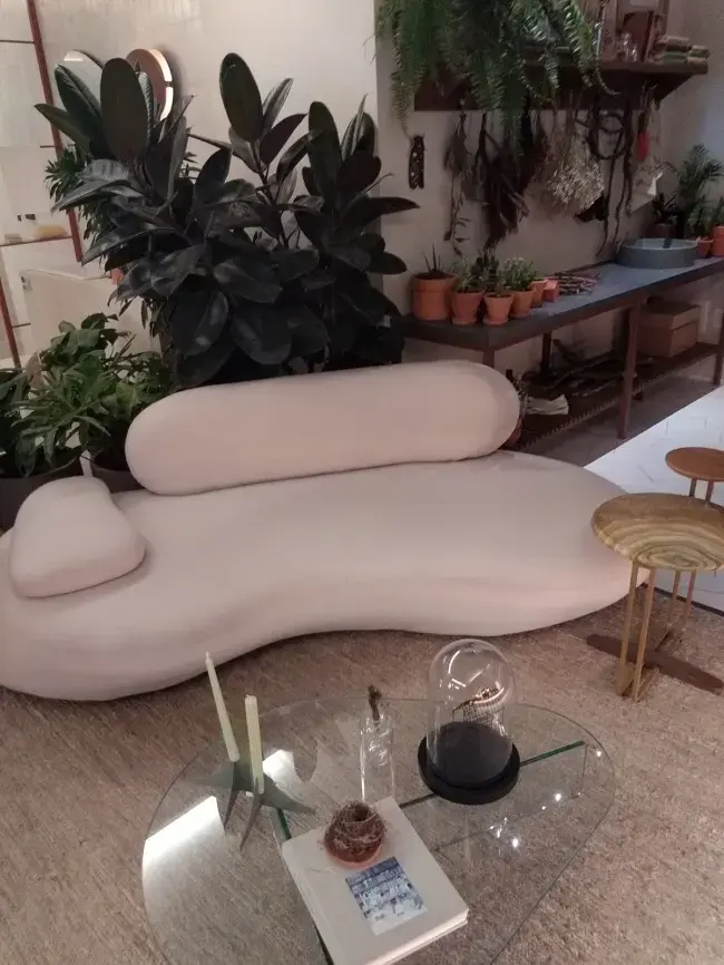 Sala de estar decorada com sofá curvo e uma mesa de centro de vidro em formato orgânico. Foto: Nathalia Inson