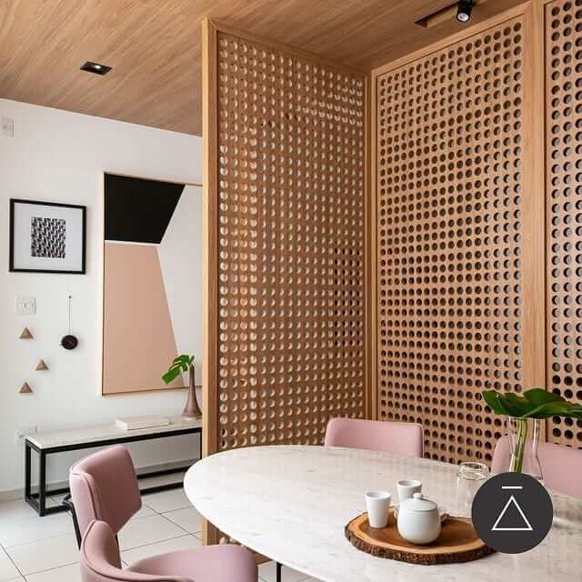 Sala de jantar com divisória de madeira e cadeiras cor de rosa na decoração