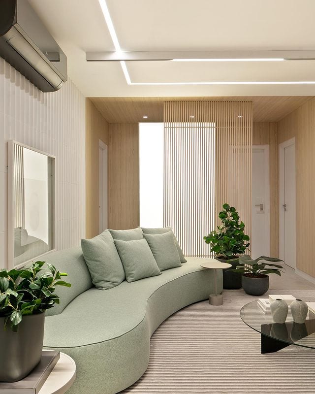 Sala moderna com sofá curvo e divisória de madeira para sala com ripas de madeira para entrada de luz