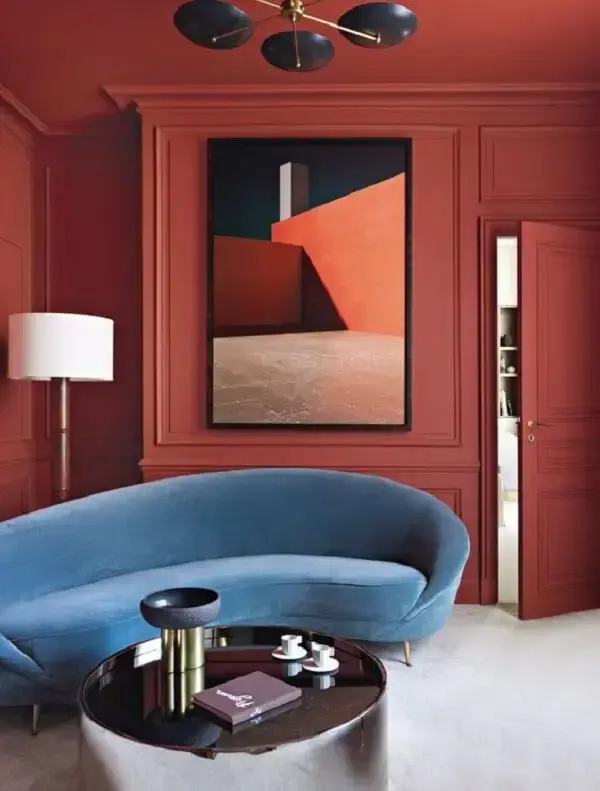 Sala vermelha com sofá curvo azul. Fonte: Marie Clarie Italia