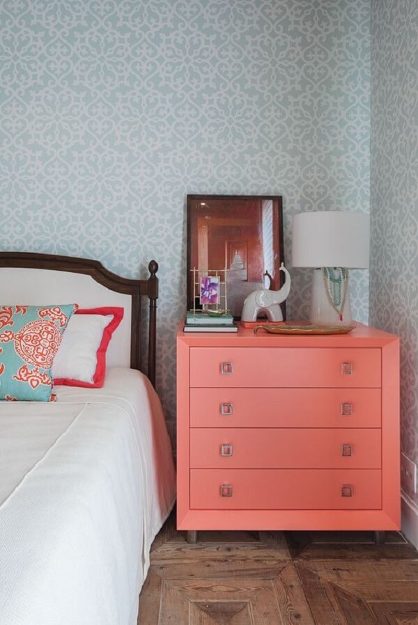 Cômoda colorida coral no quarto de casal elegante com papel de parede azul 