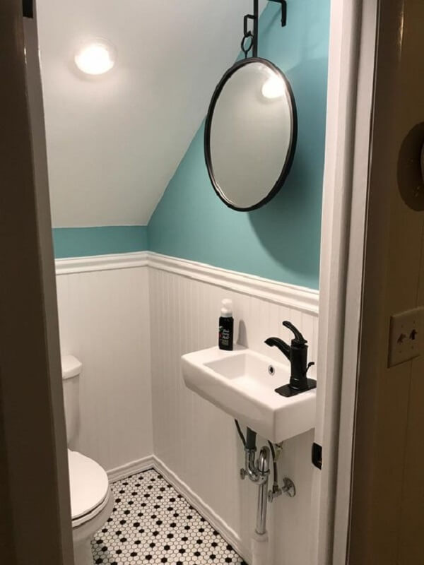 A torneira preta se contrasta com a cuba branca do banheiro embaixo da escada. Fonte: The Bath Outlet