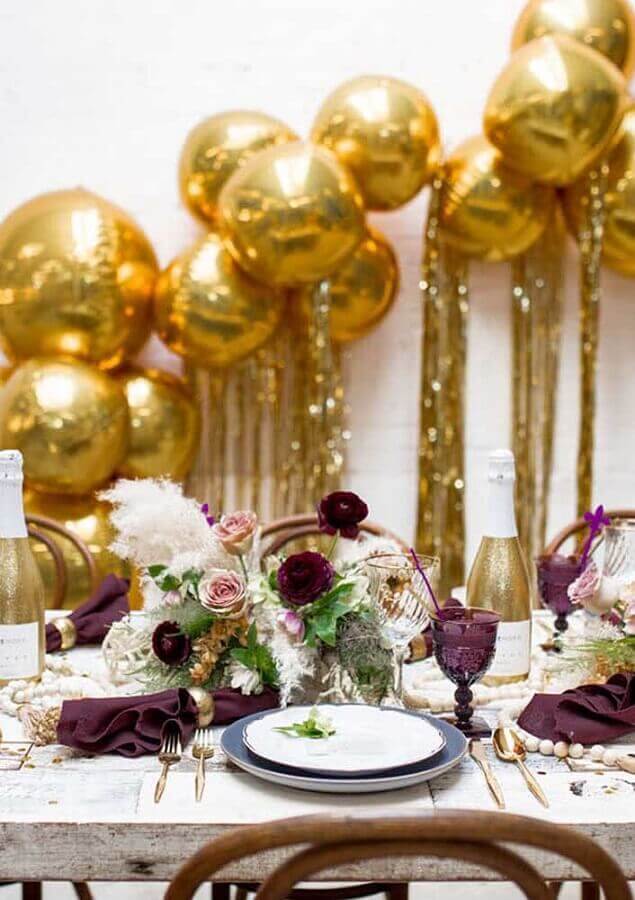 Balões dourados para mesa de ano novo decorada com arranjo de flores Foto Decor Fácil