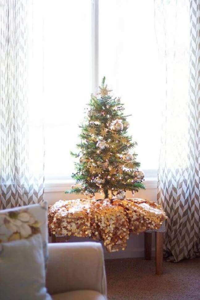 Banco da sala de estar com mini árvore de natal e manta dourada