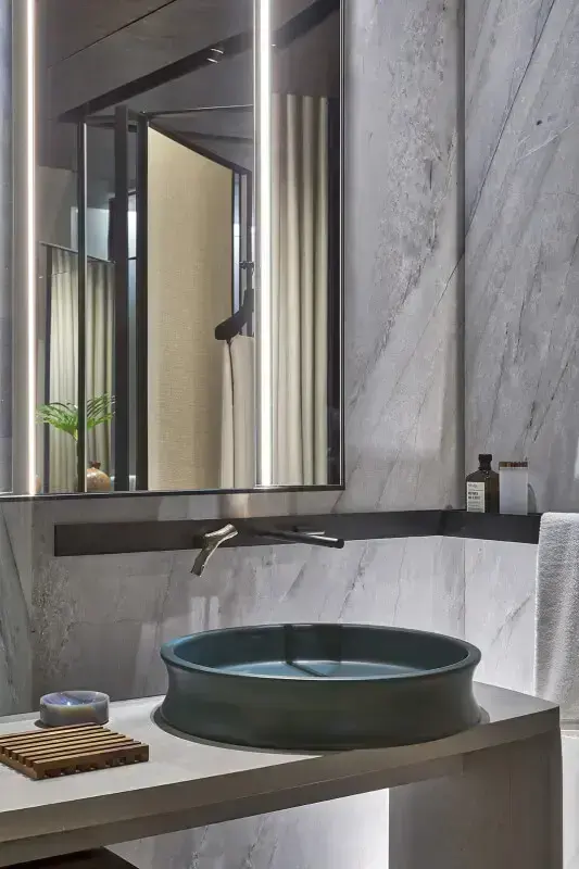 Banheiro com cuba redonda cinza e torneira de parede