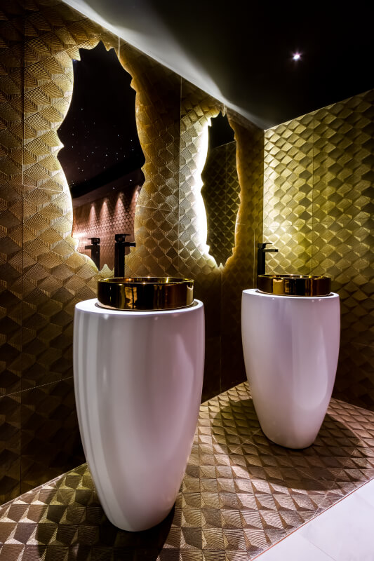 Banheiro com cuba redonda dourada e espelho moderno