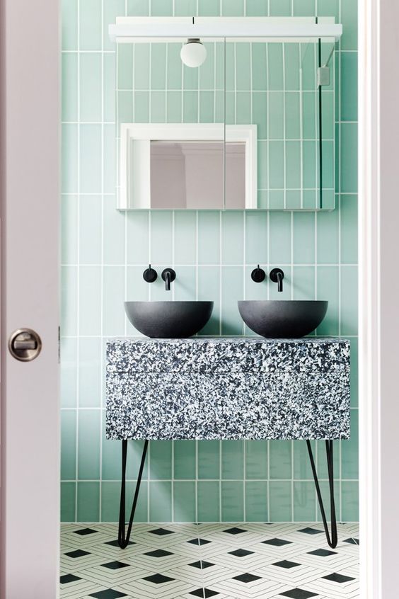 Banheiro moderno com revestimento verde pastel e bancada preta e branca