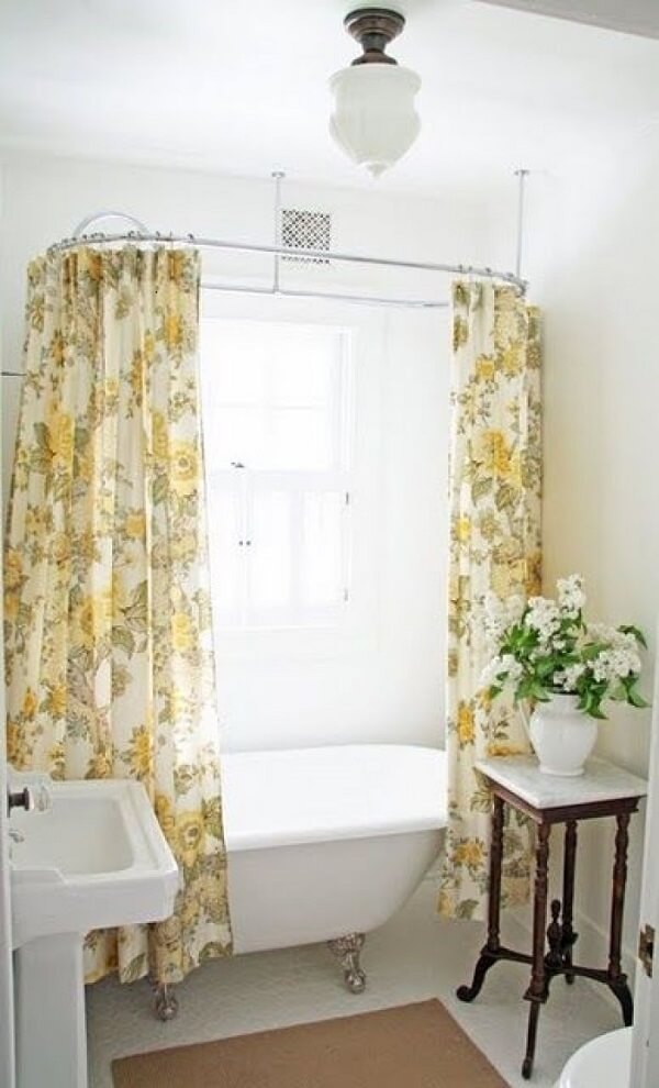 Banheiro pequeno com banheira vitoriana e cortina de flores amarelas 