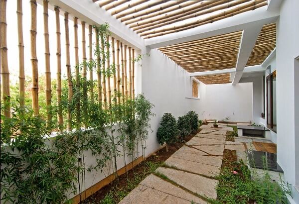 Casa com pergolado de bambu na garagem e quintal