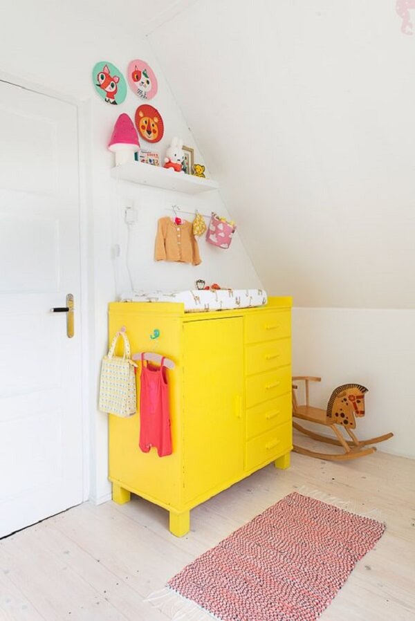 Cômoda colorida amarela no quarto de bebê