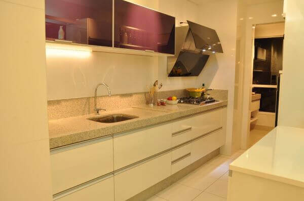 Cozinha planejada com armário de vidro roxo e bancada de granito bege