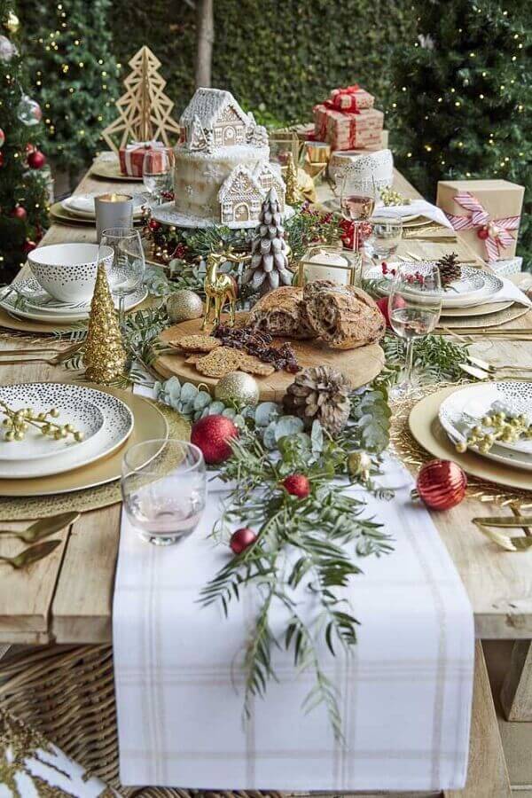 Decoração rústica para mesa de ceia natalina com folhagens e pinhas Foto Better Homes and Gardens