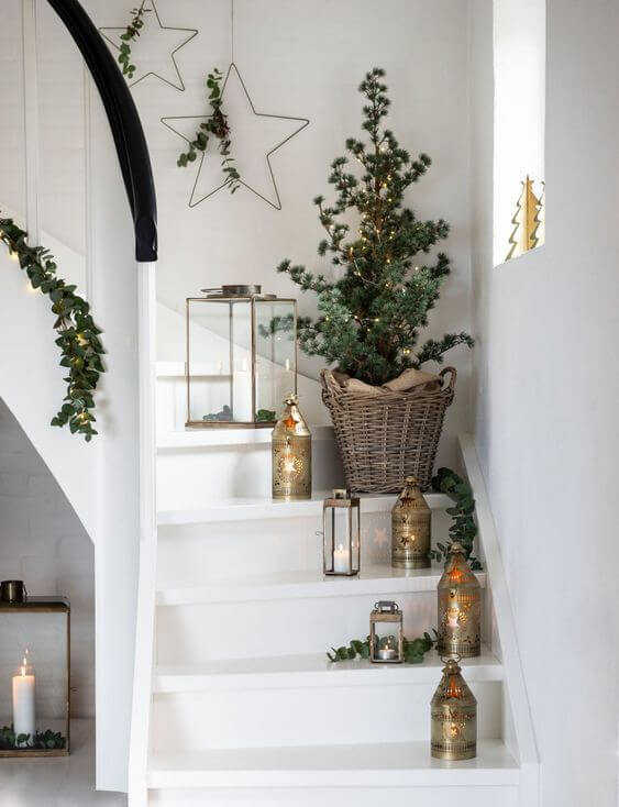 Escada decorada com mini arvore de natal e luminárias douradas