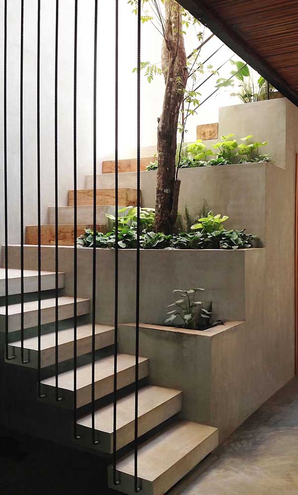 Escadas modernas com piso de cimento queimado e decoração de plantas