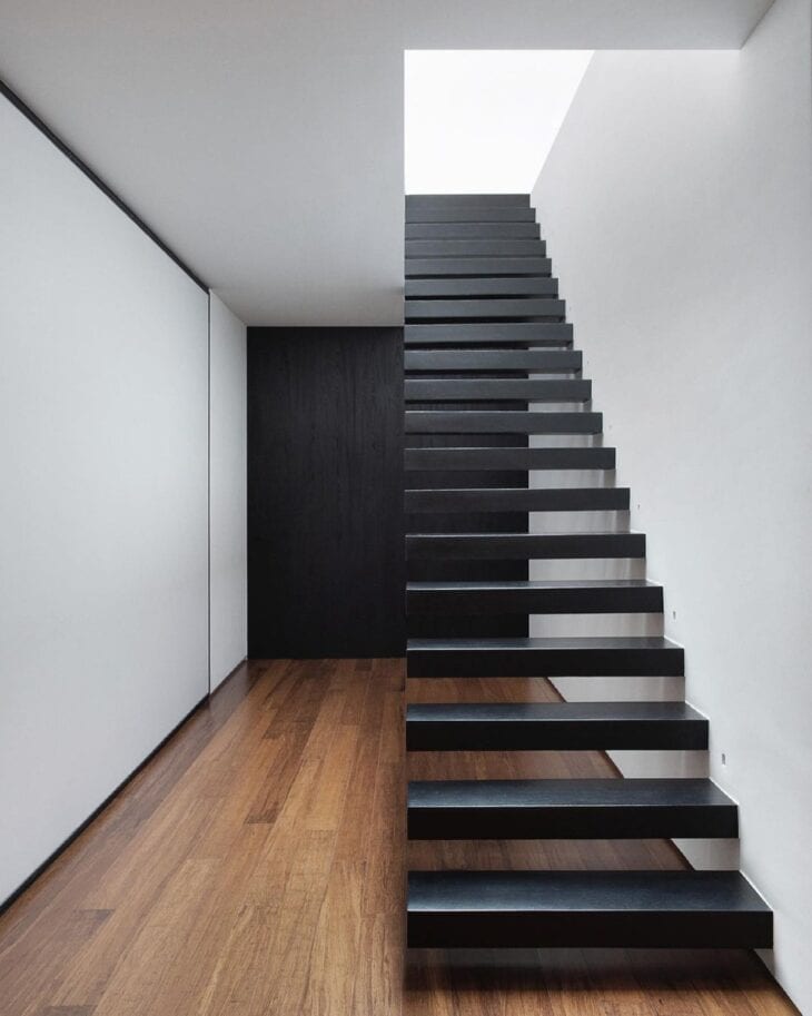 Escadas modernas pretas na casa com piso de madeira