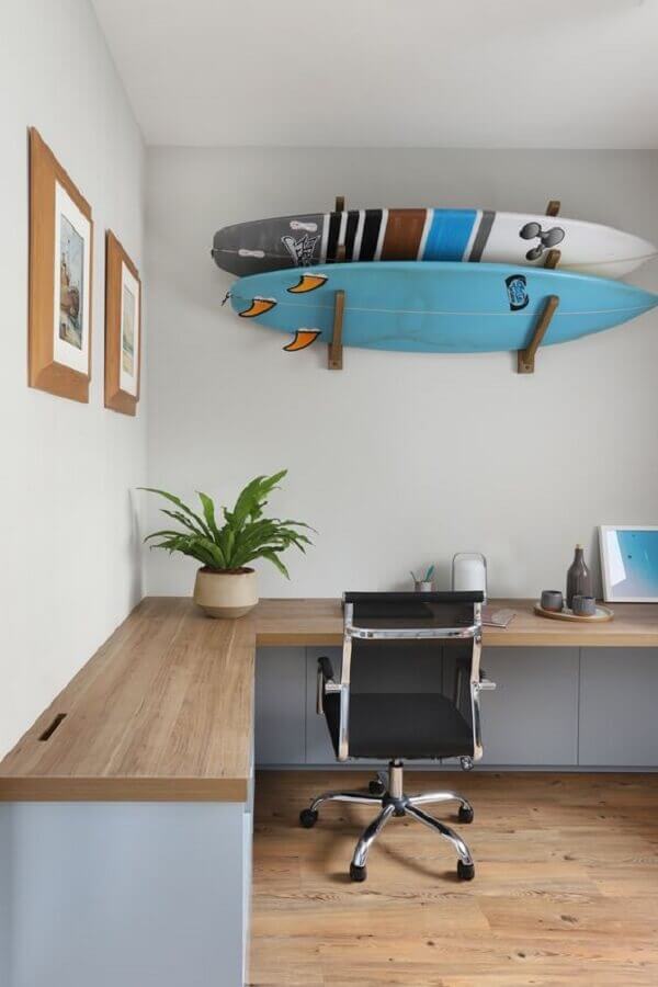 Escritório decorado com bancada de trabalho de canto e pranchas de surf Foto Gabriela Toledo Arquitetura