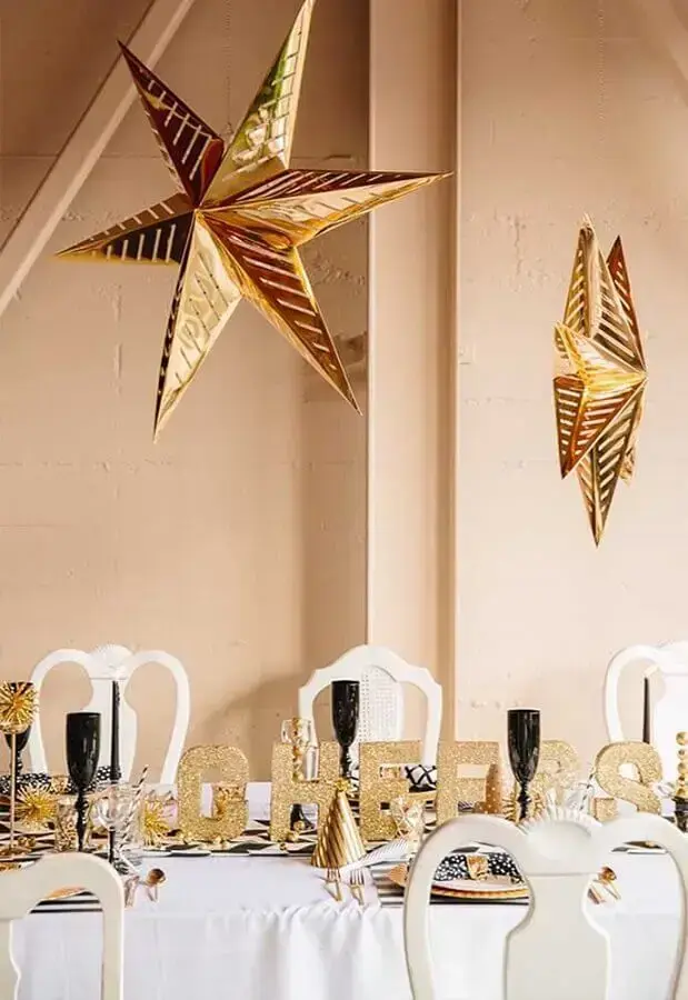 Mesa de ano novo decorada em branco e dourado com taças pretas Foto Inspired By This