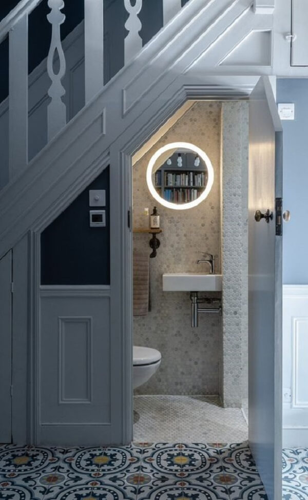 O espelho com led traz um toque charmoso para o banheiro pequeno embaixo da escada. Fonte: Nonie Decamila