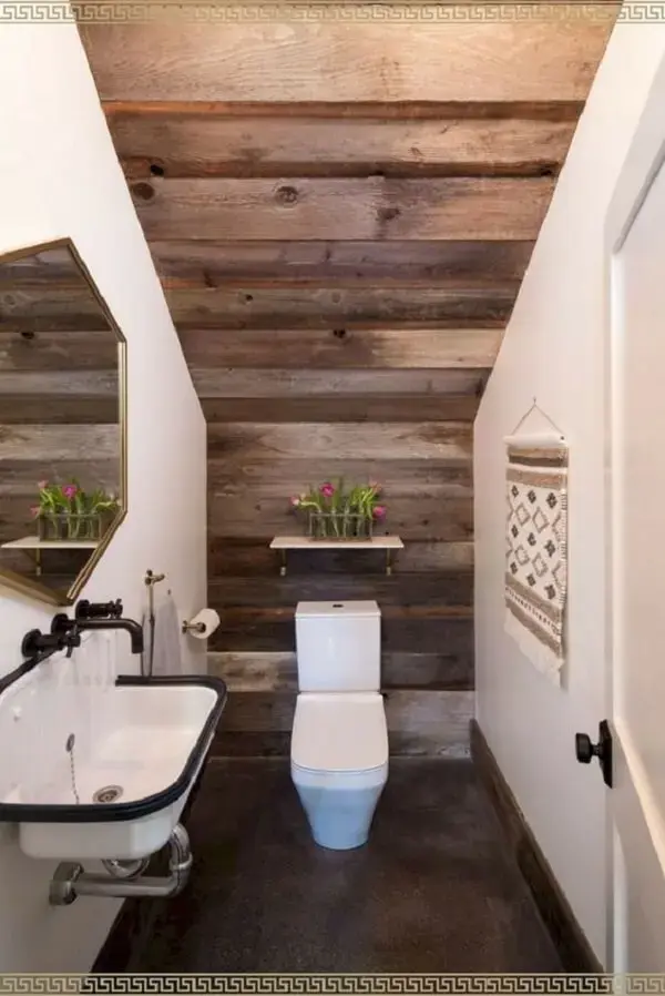 O revestimento em madeira traz um toque rústico para o décor do banheiro embaixo da escada. Fonte: Kate Rimando